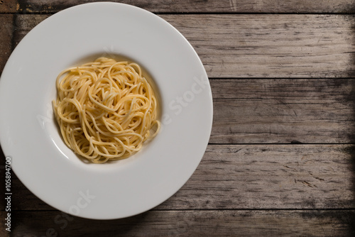 Cooked spaghetti in plate on rustic wood