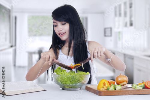 Young woman cooks salad at home