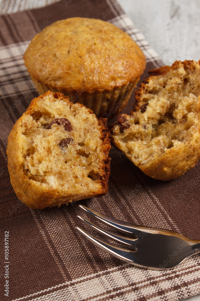 Fresh muffins with oatmeal and raisins with fork on checkered tablecloth, delicious healthy dessert Fresh muffins with oatmeal and raisins with fork on checkered tablecloth, delicious healthy dessert