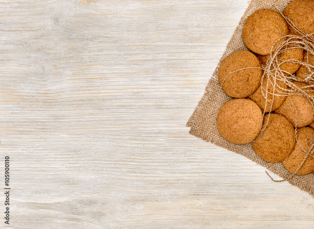 Oatmeal cookies on the burlap on white wooden background Oatmeal cookies on the burlap on white wooden background