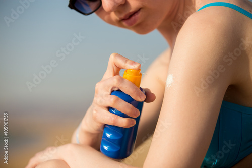 Spraying sunscreen lotion on shoulder