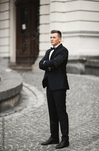 Sexy man, groom posing in old city
