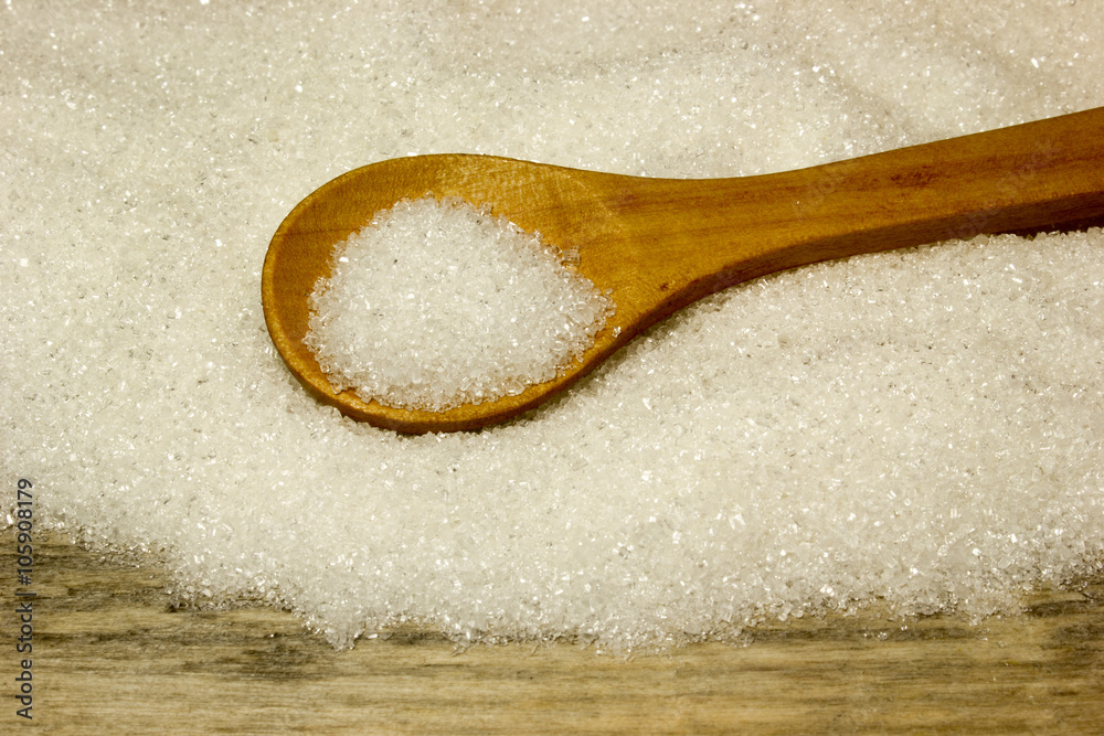 Sugar and wooden spoon on wooden background Sugar and wooden spoon on wooden background