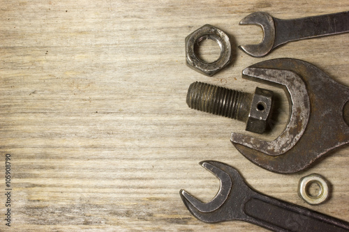 Wrench, nuts and bolts on wooden background