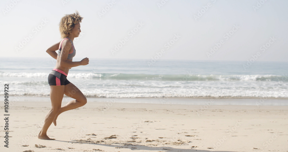 Slender fit young woman afrcian-american running on the beach in slow motion Slender fit young woman afrcian-american running on the beach in slow motion