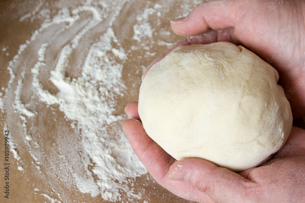 The dough in his hands on the table with flour. The dough in his hands on the table with flour.