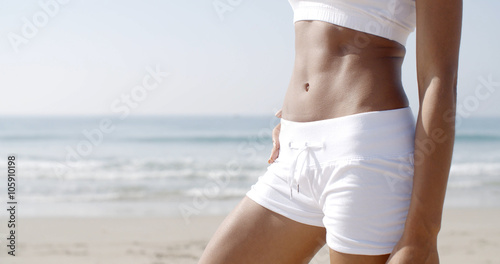 Young woman in a white bikini on beach on a sunny summer day