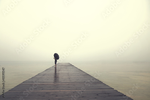 woman with umbrella contemplates peacefully in front of a myster