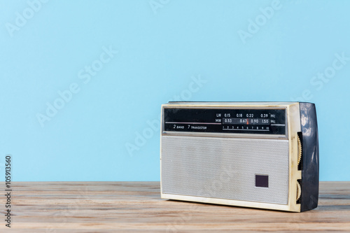 Old retro radio receiver on wooden table and blue background