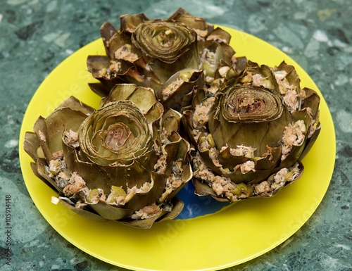 Stuffed artichoke on a plate in blurry green background, typical maltese dish artichoke. Mediterranean cuisine photo