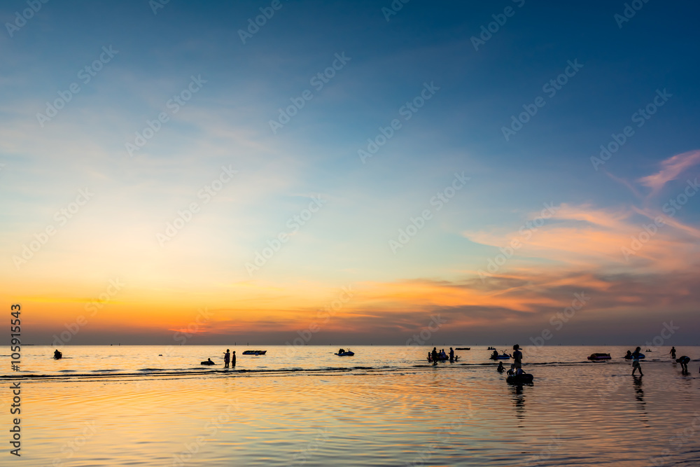 Beautiful sunset at sea beach and people silhouette.