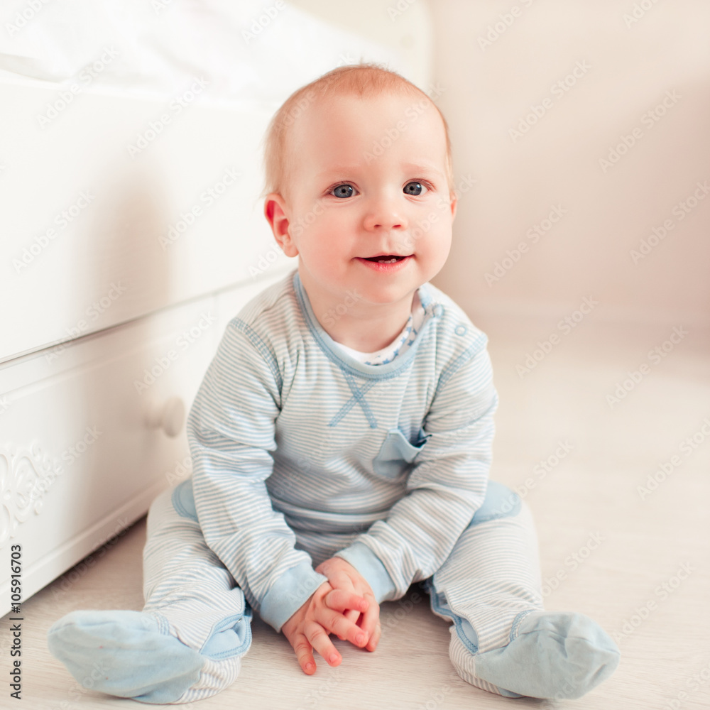 Smiling baby boy sitting on floor in room. Looking at camera. Cheerful. Childhood. Smiling baby boy sitting on floor in room. Looking at camera. Cheerful. Childhood.