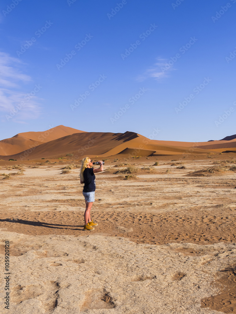 Eine Frau trinkt aus einer Wasserflasche, Sossusvlei, Naukluft Park, Rand der Namib Wüste, Hardap, Namibia , Afrika