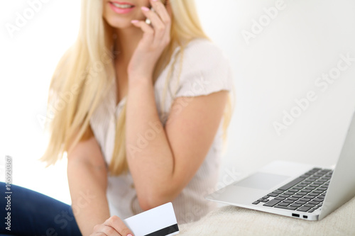 Happy woman doing online shopping at home . Close- up of a hand holding a credit card next to a laptop