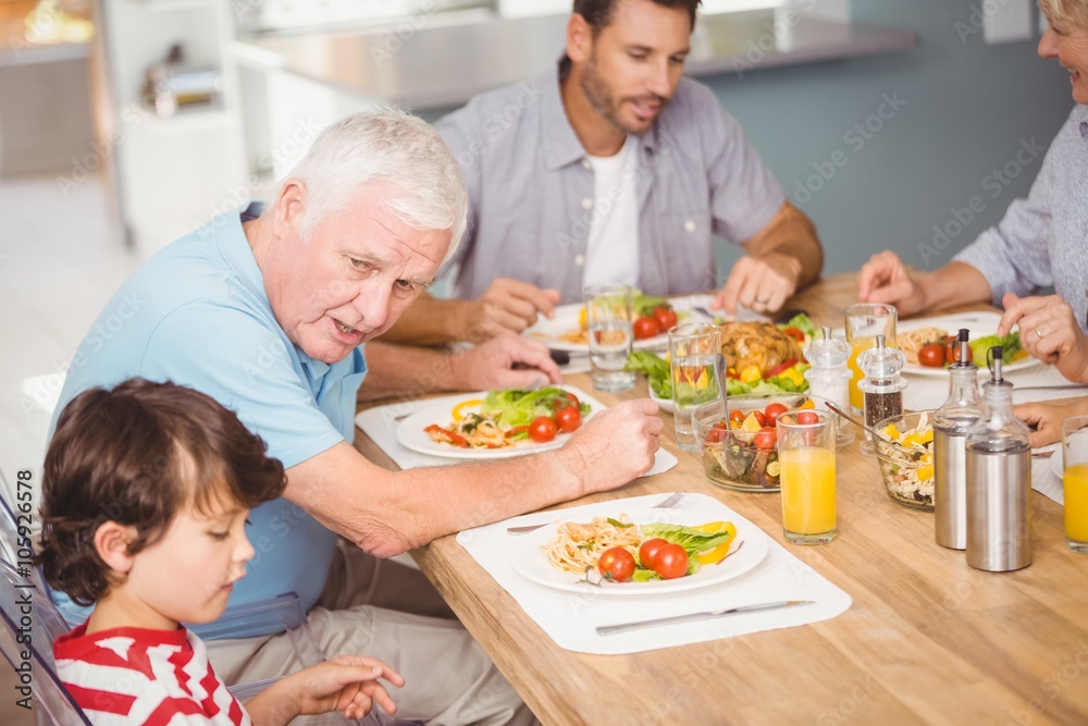 Grandfather assisting grandson while having breakfast Grandfather assisting grandson while having breakfast