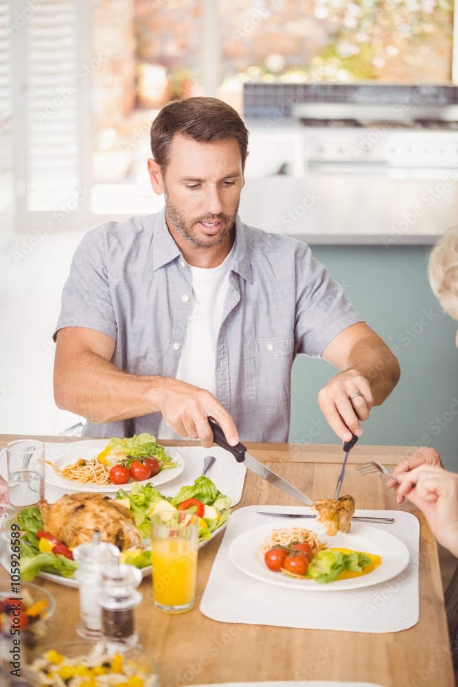 Man serving meat in plate while having lunch Man serving meat in plate while having lunch