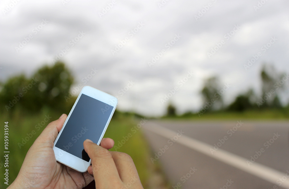 hand holding the smartphone on blur of road running through the