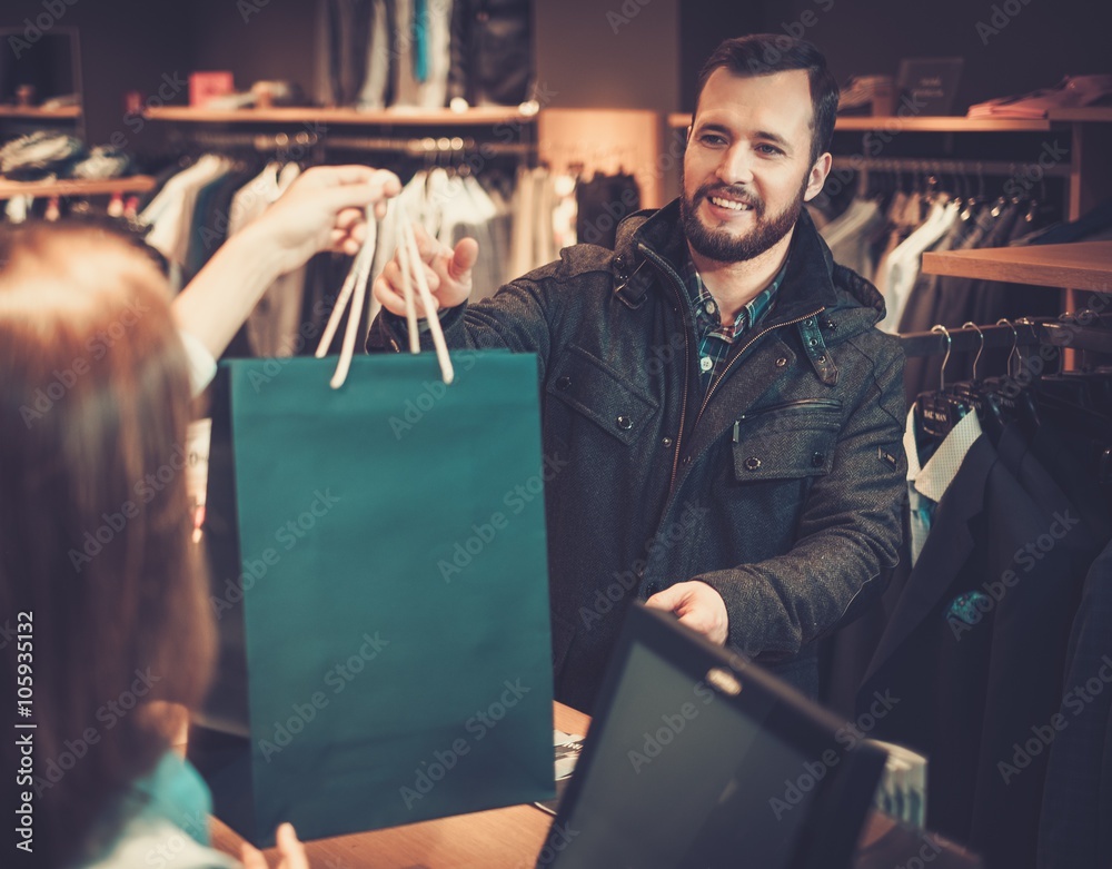 © Nejron Photo - Happy handsome man taking shopping bag from saleswoman in a suit shop. © Nejron Photo - Happy handsome man taking shopping bag from saleswoman in a suit shop.