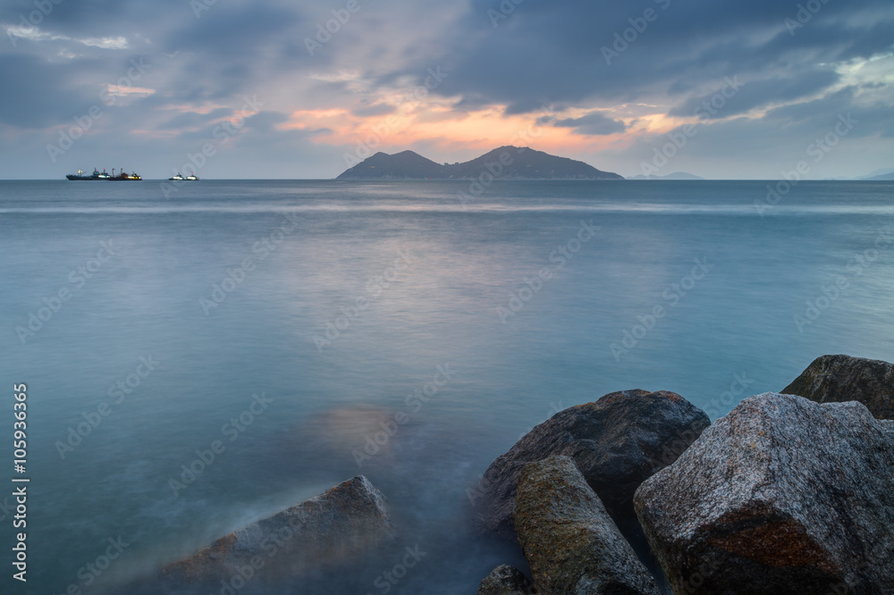 View of rocks, ocean and cloudy sky at the Cheung Chau Island in Hong Kong, China, at sunset.