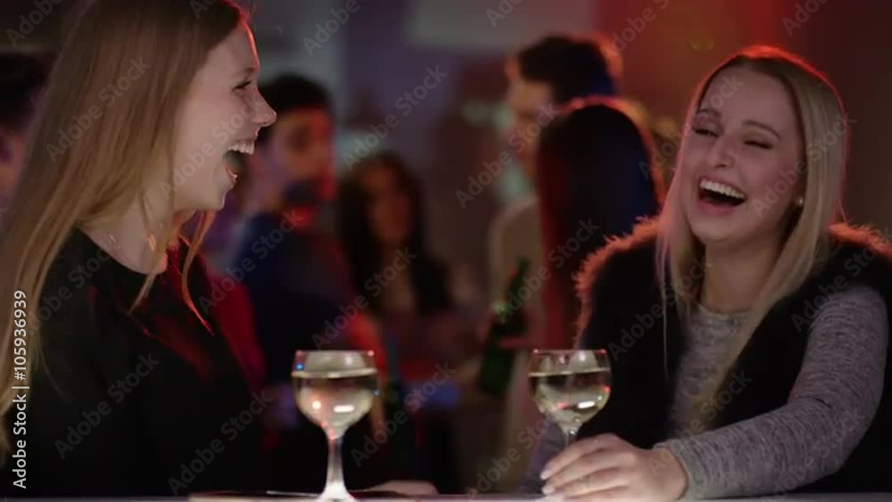 two attractive girls at bar in club doing high five two attractive girls at bar in club doing high five