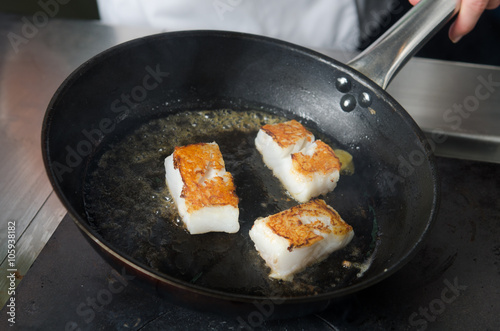 Pan fried golden fish fillet cubes, frying in real butter, in a non stick rustic pan.