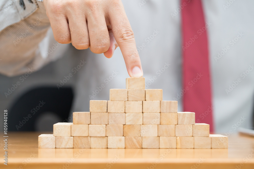 Hand of businessman pointing on top of wood block Hand of businessman pointing on top of wood block