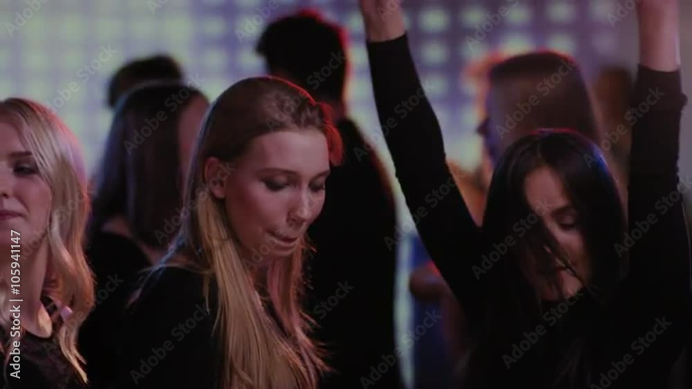three attractive girls having fun dancing on dancefloor at club