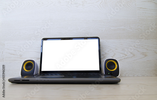 Laptop with blank screen and multimedia speakers. Wooden background.