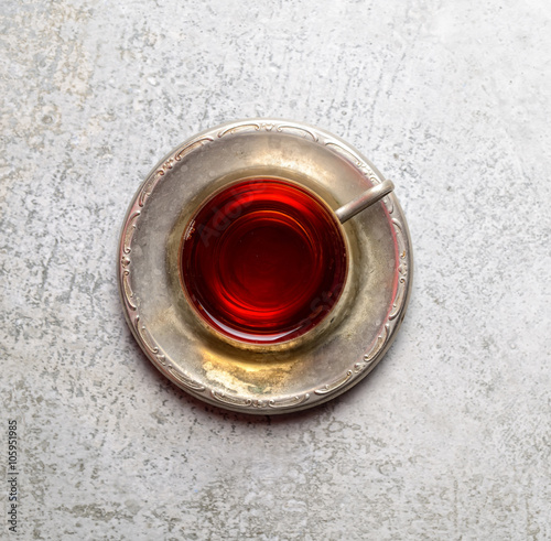 Vintage tea in a mug on a metal saucer on a gray background 