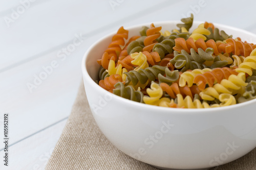 Raw fusilli pasta in a white bowl photo