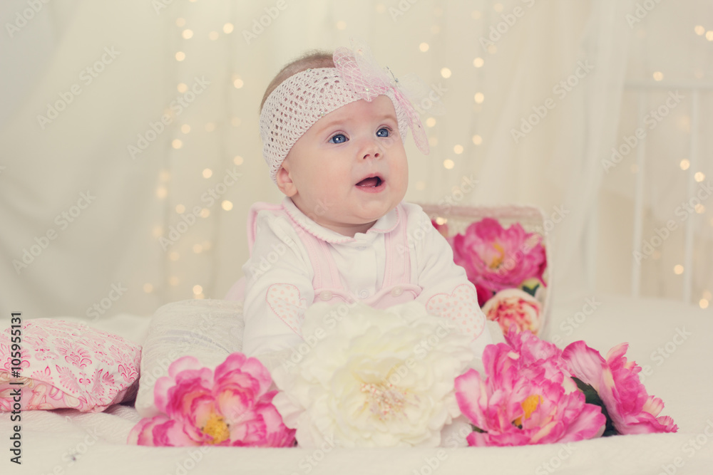 Baby girl is lying on bed with pink flowers Baby girl is lying on bed with pink flowers