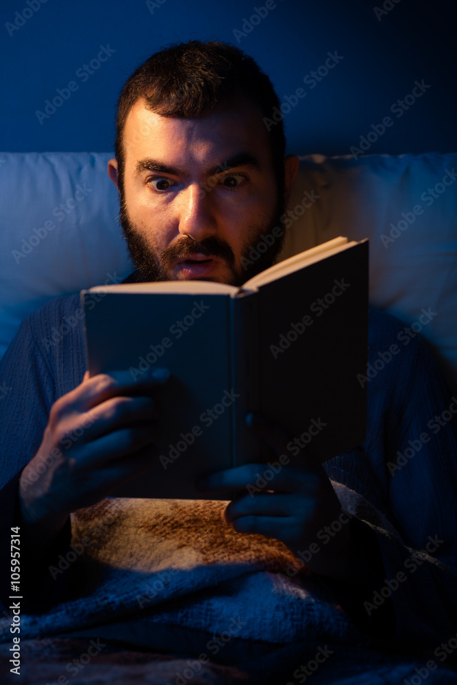 Surprised Man Reading a Book at Night in a Bed Surprised Man Reading a Book at Night in a Bed