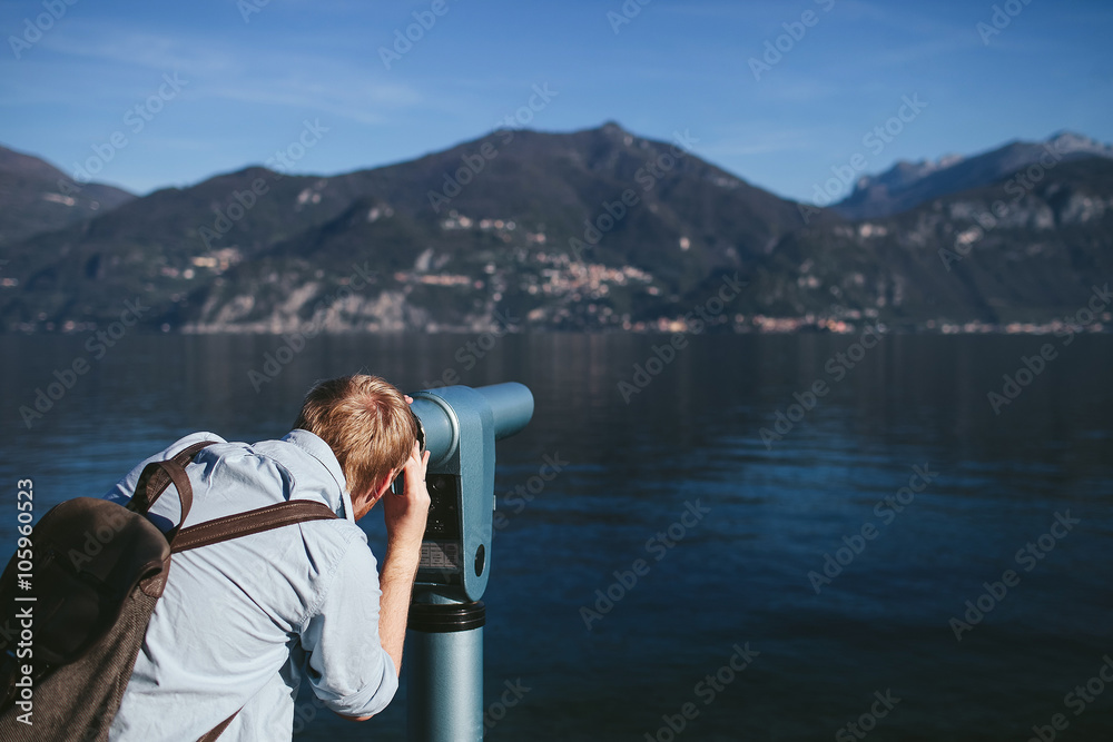man looking in the telescope on the shore of Lake Como