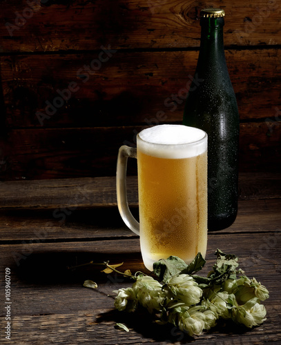 beer in glass, bottle and hops on a wooden background