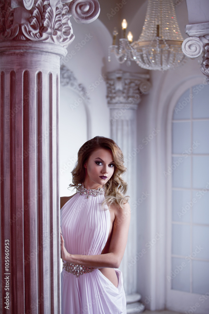 Portrait of young sexy woman in a white dress, luxurious hall with columns