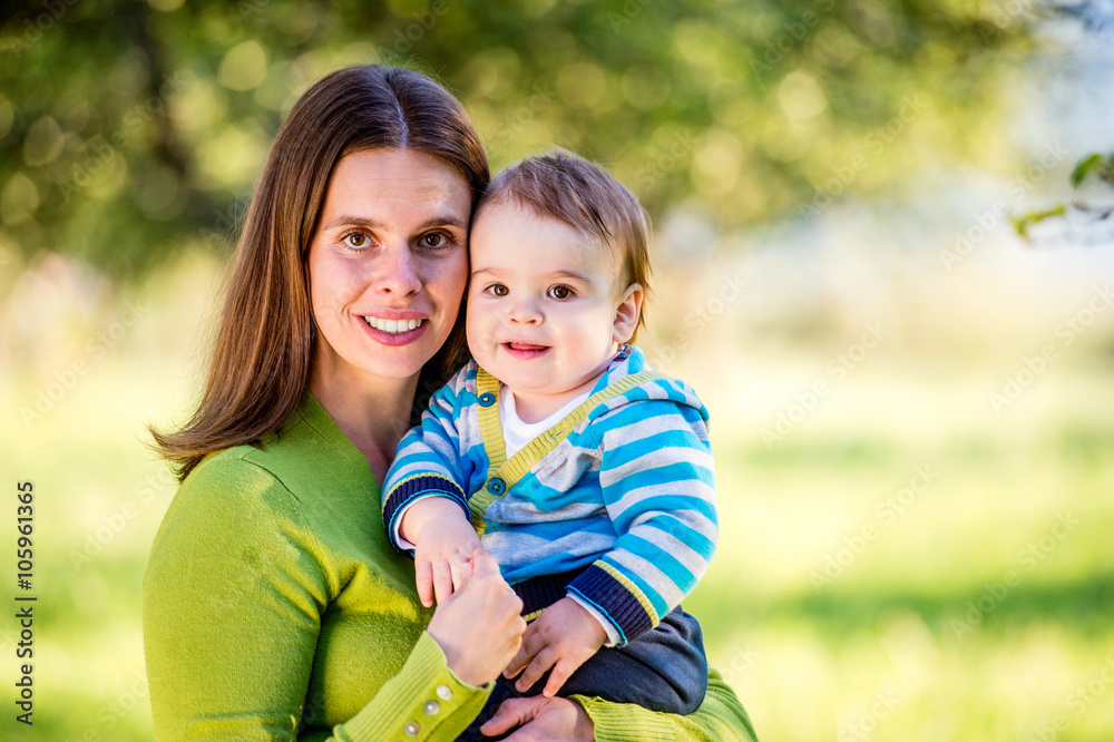 Mother holding little son in her arms, sunny nature Mother holding little son in her arms, sunny nature