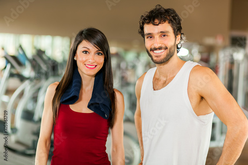 Woman posing with her fitness trainer in the gym