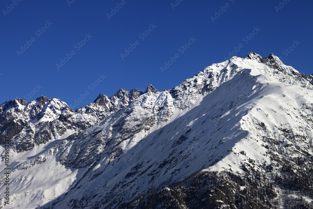 Snowy rocks and blue clear sky at nice sun day