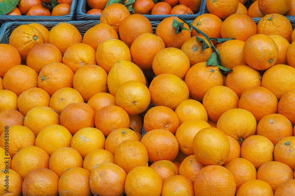 Pattern created by assortment of several orange fruits on a market stall, ideal for background.