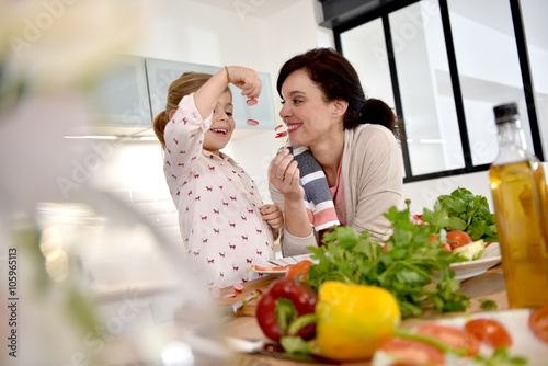 Mom and daughter cooking together in modern kitchen