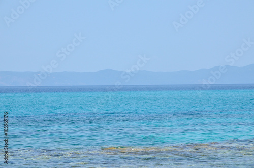 Turquoise sea water with land in distance and blue sky