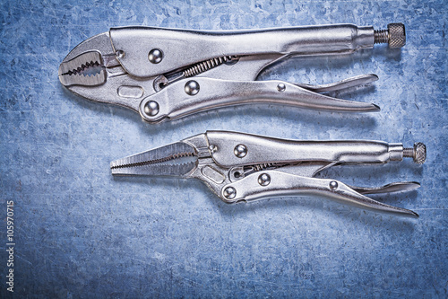 Locking pliers with jaws on metallic background construction con photo