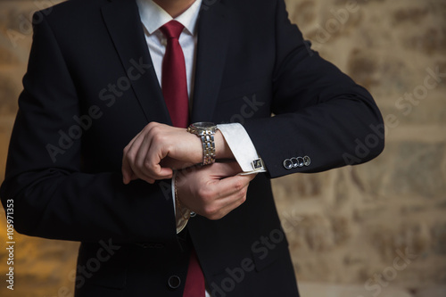Elegant businessman correcting his cufflinks and sleeve