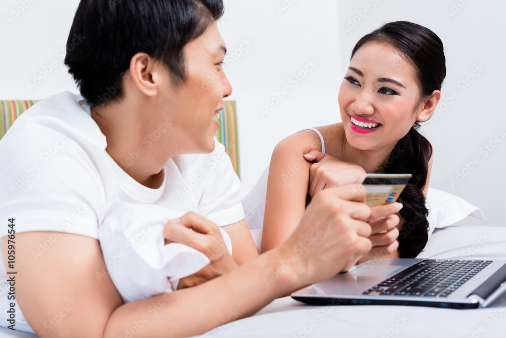 Chinese couple shopping online from their bedroom Chinese couple shopping online from their bedroom