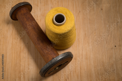 Empty Wooden Thread Spool Beside Yellow Thread