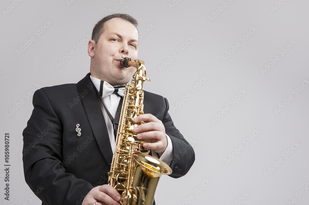 Fototapeta premium Music Concept and Ideas. Portrait of Caucasian Player in Suit Playing Sax