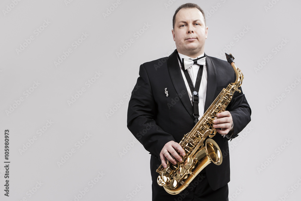 Naklejka premium Man with Saxophone in Suite Posing Against White Background