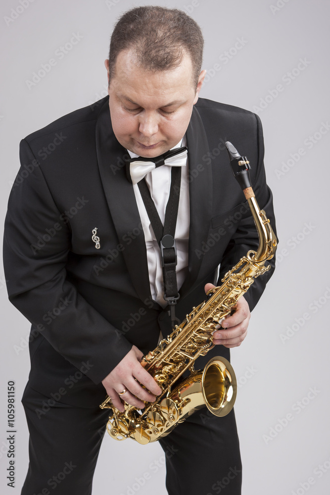 Naklejka premium Caucasian Man in Suite with Saxophone. Posing Against White.