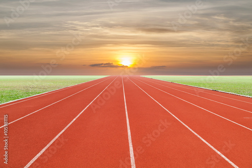 Running track with green grass and sky sunset .