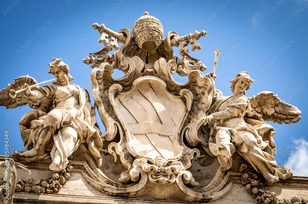 Sculpture of two angels with trumpets and the coats of arms of the Holy See and Vatican City State in the form that combines two crossed keys and a tiara.